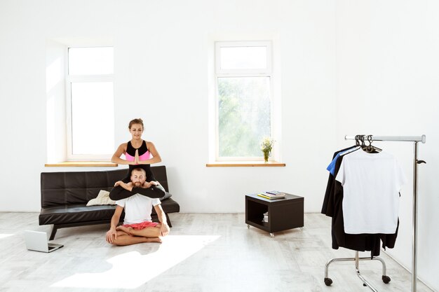Joven pareja deportiva hermosa meditando, practicando asanas de yoga en casa.