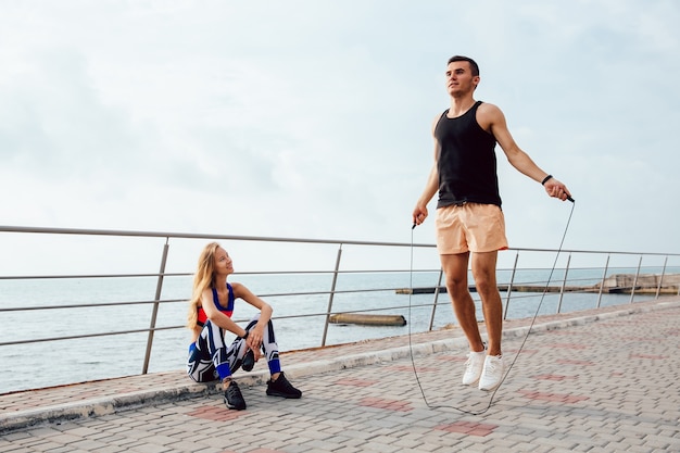 Foto gratuita joven pareja deportiva trabajando juntos en el muelle, cerca del mar.