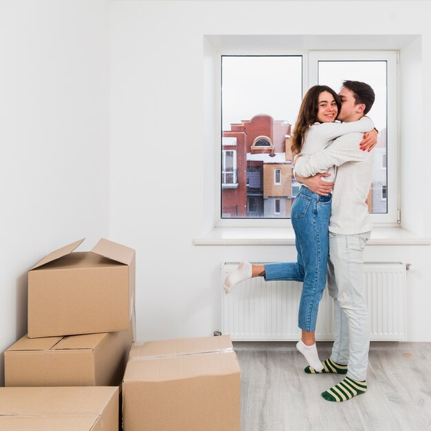 Joven pareja disfrutando en su nuevo hogar con cajas de cartón.