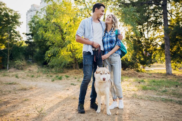 Joven pareja elegante caminando con perro en la calle. hombre y mujer felices junto con la raza husky,