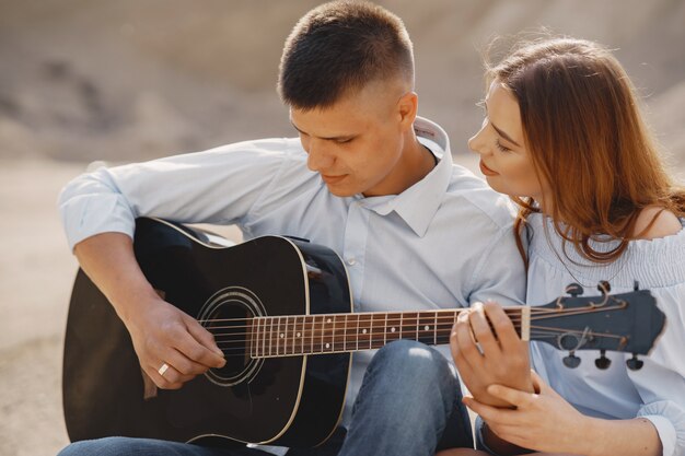 Joven pareja enamorada, novio tocando la guitarra