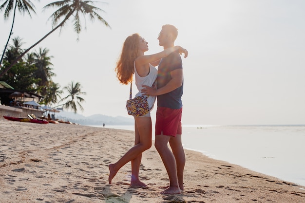 Joven pareja de enamorados felices en la playa de verano divirtiéndose juntos