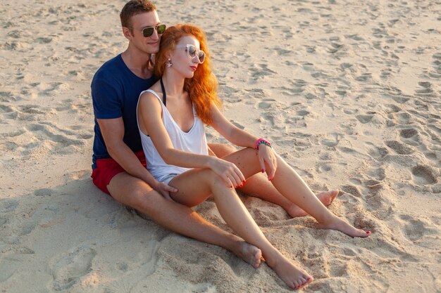 Joven pareja de enamorados felices en la playa de verano divirtiéndose juntos