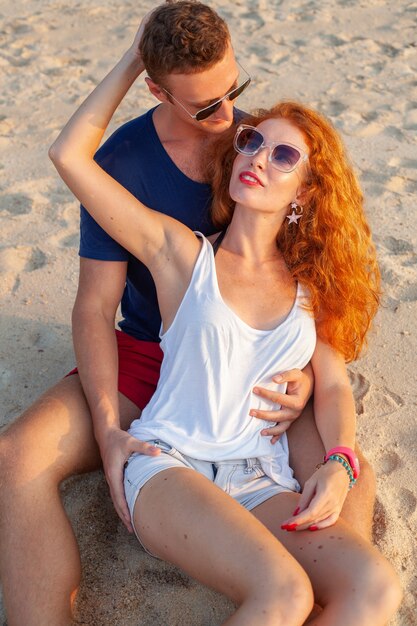 Joven pareja de enamorados felices en la playa de verano divirtiéndose juntos