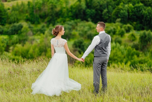 Joven pareja de enamorados, novio y novia en vestido de novia en la naturaleza.