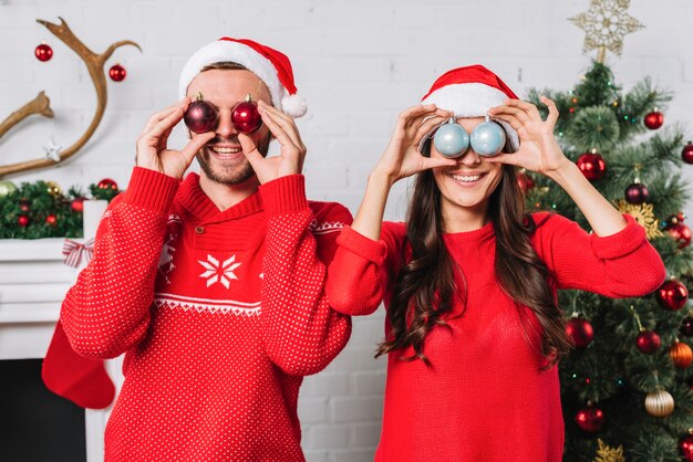 Joven pareja feliz con adornos de Navidad