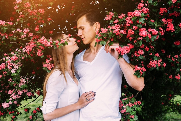 Joven pareja feliz en el amor al aire libre. Amando al hombre y a la mujer en un paseo por un parque floreciente de primavera