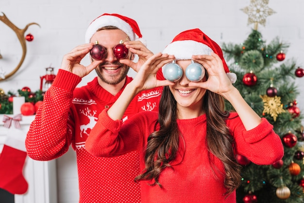 Joven pareja feliz con bolas ornamentales