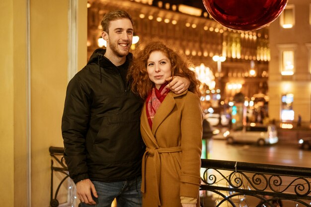 Joven pareja feliz caminando por la ciudad por la noche