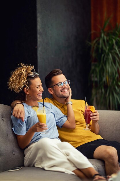 Joven pareja feliz con cócteles de frutas disfrutando en su tiempo juntos