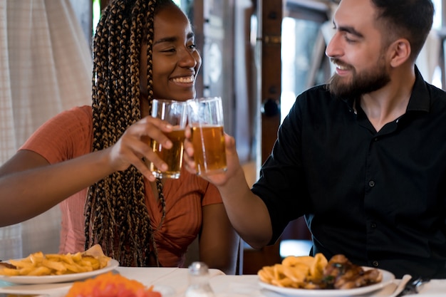 Joven pareja feliz disfrutando de una comida juntos mientras tienen una cita en un restaurante.