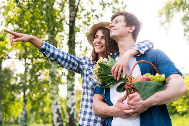 Joven pareja feliz elegir lugar de picnic en la naturaleza