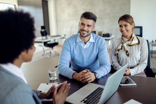 Una joven pareja feliz reunida con un agente inmobiliario en la oficina