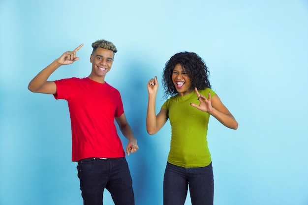 Joven pareja feliz en ropa casual posando en la pared azul