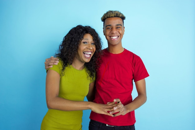 Joven pareja feliz en ropa casual posando en la pared azul