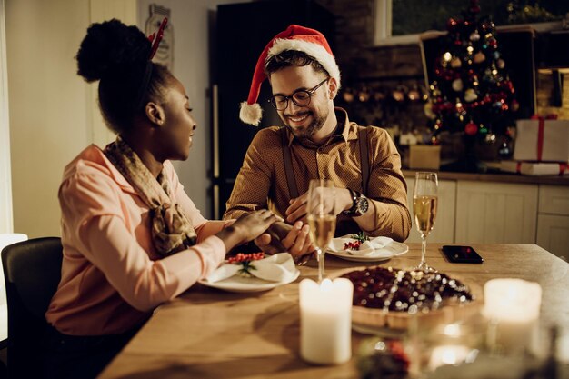 Joven pareja feliz tomados de la mano durante la cena de Navidad en casa