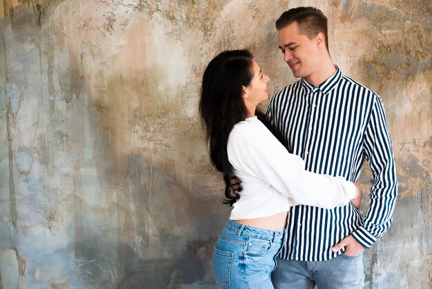 Joven pareja hermosa abrazos contra muro de hormigón