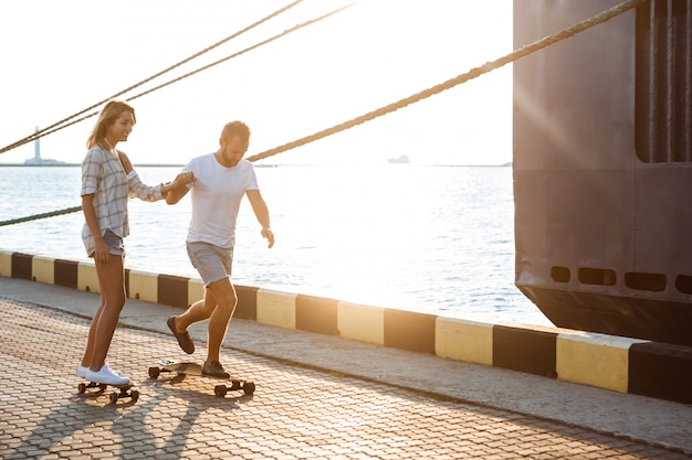 Foto gratuita joven pareja hermosa caminando en la playa, el skate.