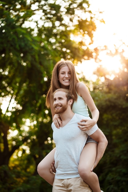 Joven pareja hermosa descansando, caminando en el parque, sonriendo, regocijándose al aire libre