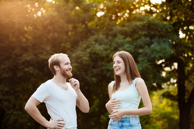 Joven pareja hermosa descansando, caminando en el parque, sonriendo, regocijándose.