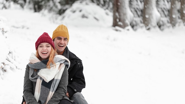 Joven pareja hermosa divirtiéndose en la nieve