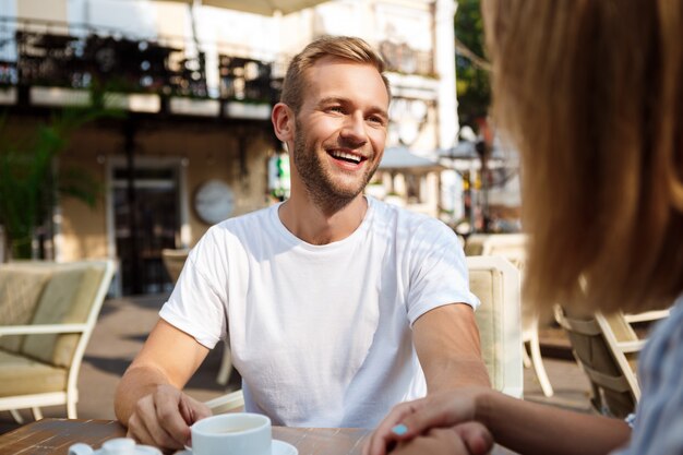 Joven pareja hermosa hablando, sonriendo, descansando en la cafetería.