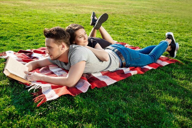 Joven pareja hermosa lectura sonriente en el parque.