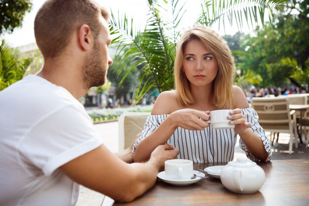 Joven pareja hermosa pelea, sentado en la cafetería.