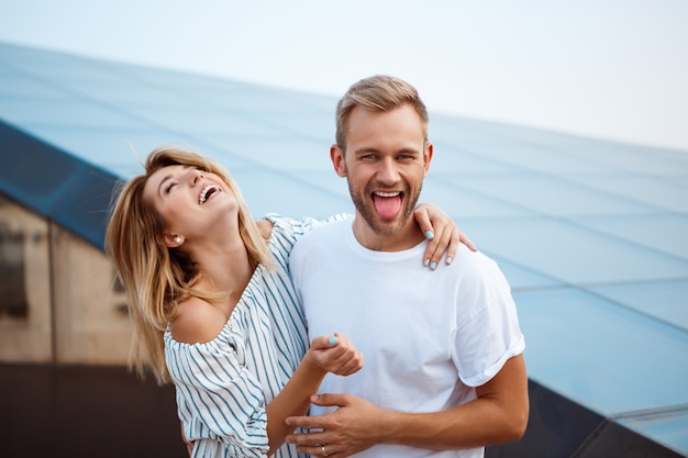 Joven pareja hermosa sonriendo, abrazándose, caminando por la ciudad