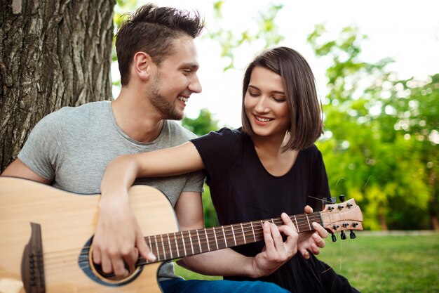 Joven pareja hermosa sonriendo, descansando en un picnic en el parque.