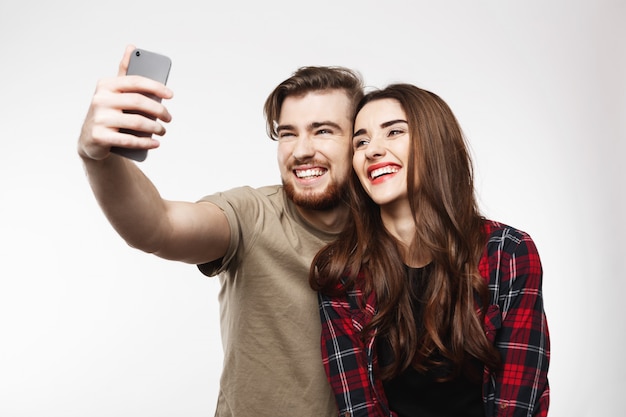 Foto gratuita joven pareja hermosa tomando fotos de sí mismos, riendo alegremente.