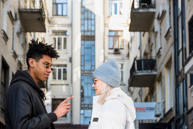 Joven pareja interracial de pie cara a cara de pie debajo del edificio