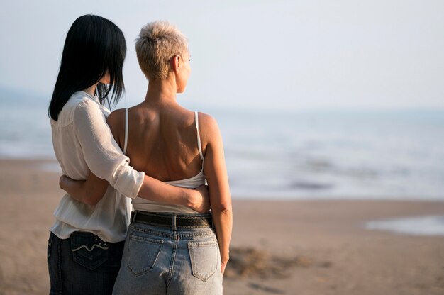 Joven pareja de lesbianas mirando al mar