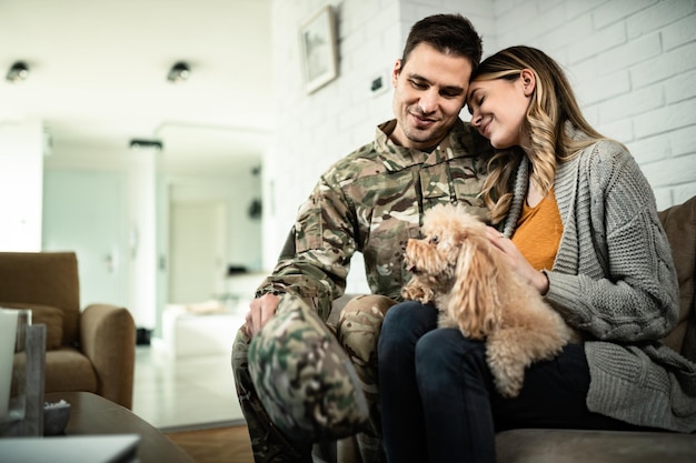 Joven pareja militar cariñosa con perro disfrutando en casa