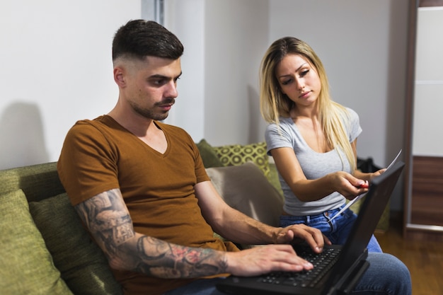 Joven pareja moderna usando laptop