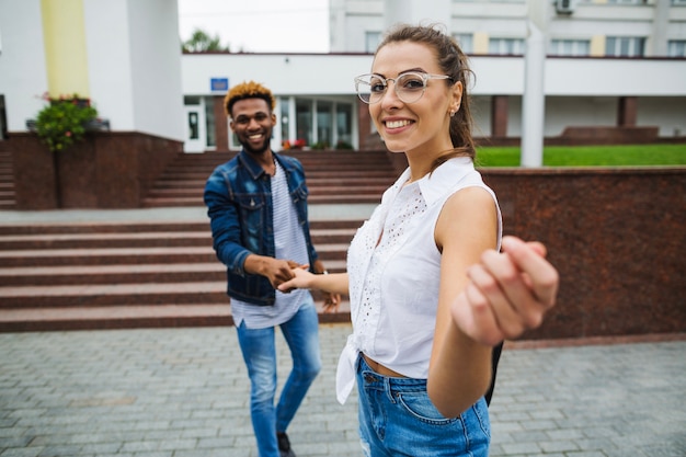 Joven pareja multirracial posando cerca de la universidad