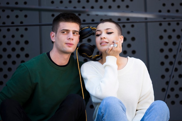 Joven pareja de pelo corto escuchando música con auriculares