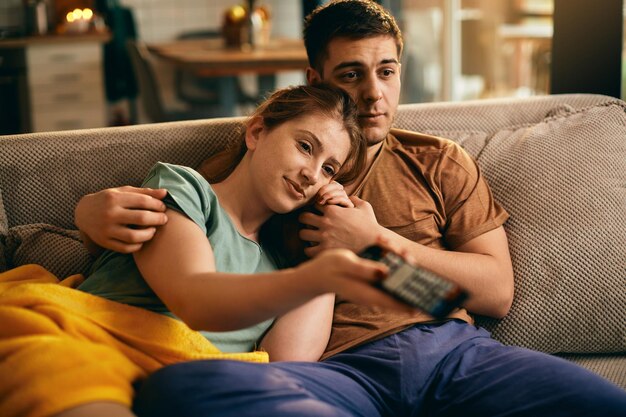 Joven pareja relajada viendo la televisión en casa