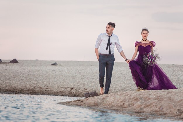 Joven pareja romántica corriendo en la playa del mar