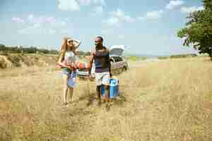 Foto gratuita joven pareja romántica internacional multiétnica al aire libre en la pradera en un día soleado de verano. hombre afroamericano y mujer caucásica haciendo picnic juntos. concepto de relación, verano.