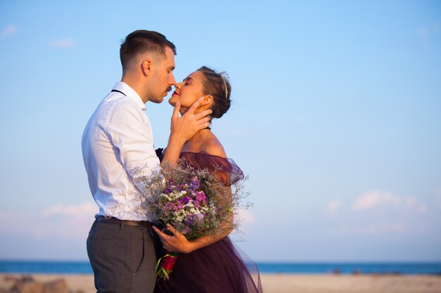 Joven pareja romántica relajante en la playa mirando el atardecer