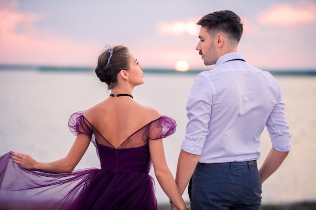 Joven pareja romántica relajante en la playa mirando el atardecer