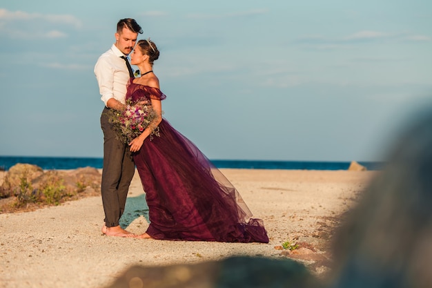 Joven pareja romántica relajante en la playa mirando el atardecer