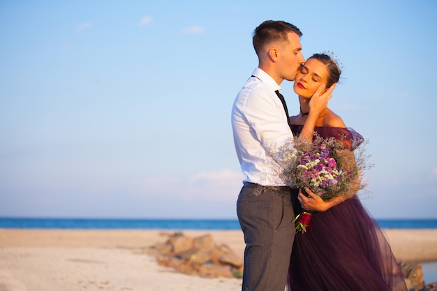 Joven pareja romántica relajante en la playa mirando el atardecer