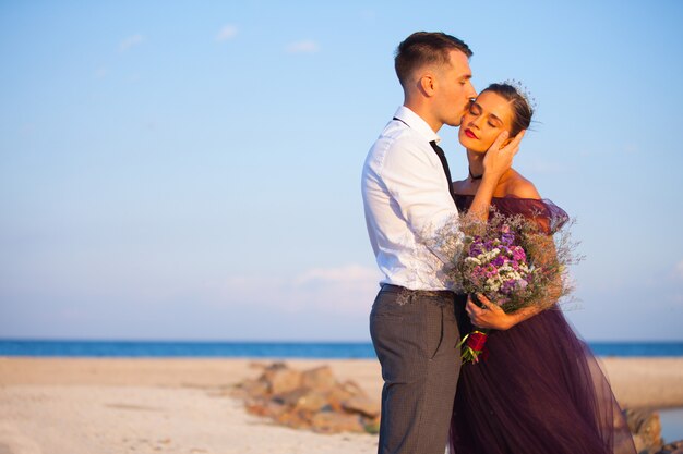 Joven pareja romántica relajante en la playa mirando el atardecer