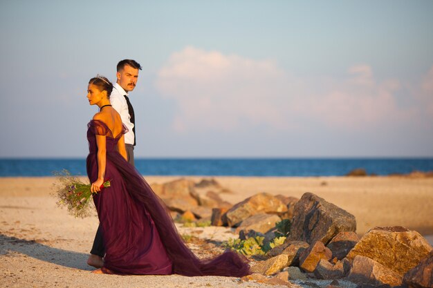 Joven pareja romántica relajante en la playa mirando el atardecer