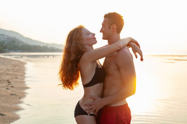 Joven pareja romántica sexy enamorada feliz en la playa de verano juntos divirtiéndose vistiendo trajes de baño