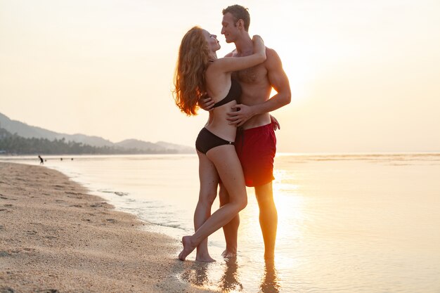 Joven pareja romántica sexy enamorada feliz en la playa de verano juntos divirtiéndose vistiendo trajes de baño