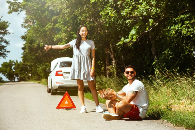 Foto gratuita la joven pareja rompió el auto mientras viajaba camino a descansar