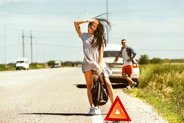 Foto gratuita la joven pareja rompió el auto mientras viajaba camino a descansar.